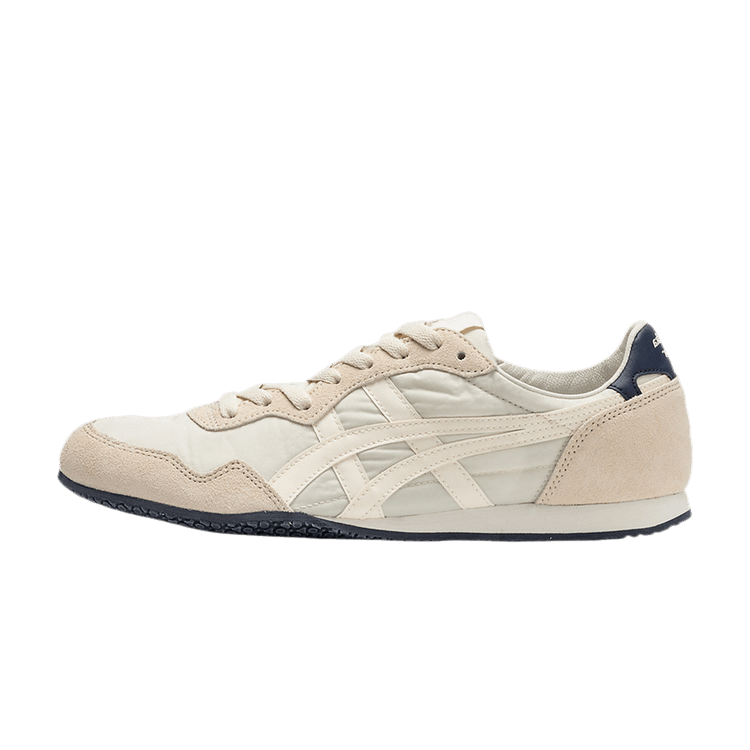 Onitsuka Tiger Serrano Oatmeal Cream zijaanzicht met crème suède, witte mesh panelen en donkerblauwe hielcounter