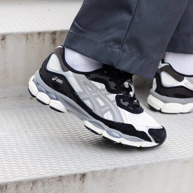 Person wearing ASICS Gel-NYC Ivory Clay Grey sneakers walking down concrete steps, showcasing stylish and comfortable trainers, exclusive sneaker design in Europe.