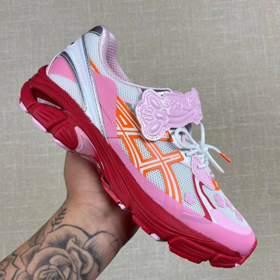 Hand holding ASICS GT-2160 Cecilie Bahnsen Habanero sneaker with pink, red, white, and orange color accents, featuring a design with unique floral and geometric details.