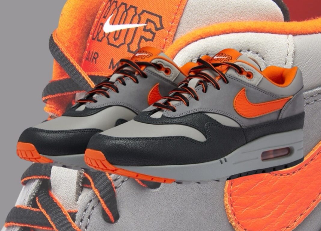 Pair of Nike Air Max 1 HUF Brilliant Orange sneakers featuring bright orange accents, black and gray panels, and a durable sole, perfect for exclusive sneaker collectors across Europe.