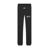 Fear of God Essentials 1977 Iron Black Full set black sweatpants featuring an elastic waistband, drawstrings, and "1977" print, part of exclusive sneakers and clothing collection.