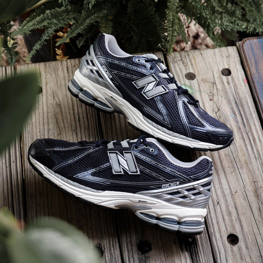 Pair of black and white New Balance 1906R Eclipse sneakers displayed on a wooden surface, highlighting sleek design and cushioning, the real deal available exclusively in Europe.