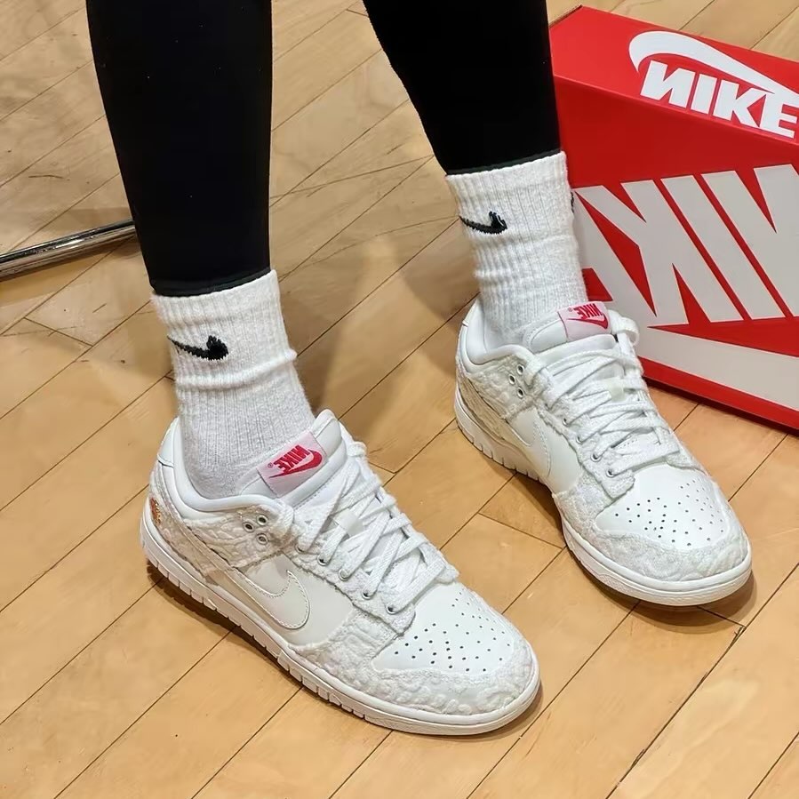 White Nike Dunk Low Give Her Flowers sneakers with subtle rose texture worn with black leggings and white Nike socks, with a red Nike shoebox in the background, exclusive sneaker style in Europe, the real deal.