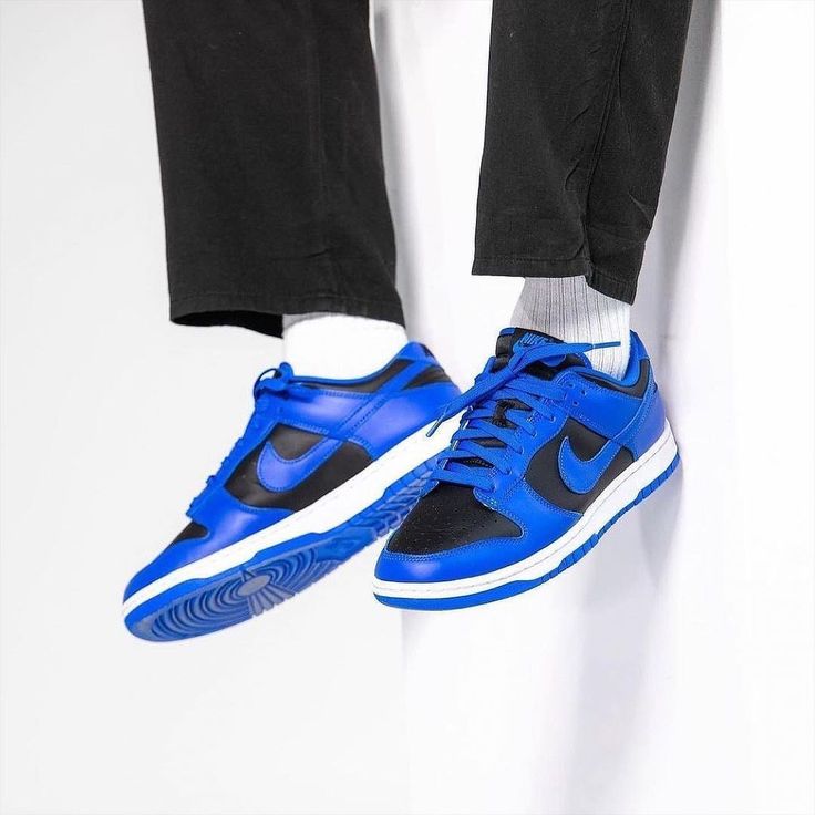Person wearing Nike Dunk Low Hyper Cobalt sneakers with bright blue and black color accents paired with white socks and black pants, highlighting exclusive European sneaker style.
