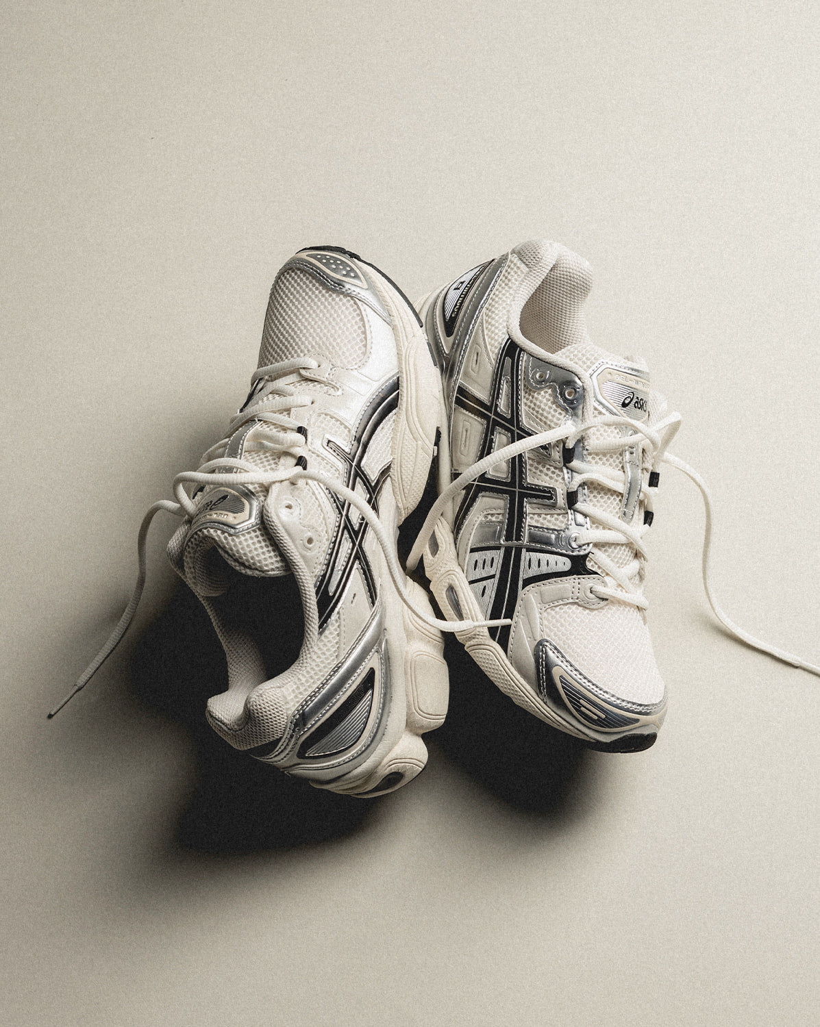 Pair of Asics Gel-Nimbus 9 Cream Black sneakers on a neutral background, featuring detailed mesh and contrasting black accents, the real deal exclusive in Europe.