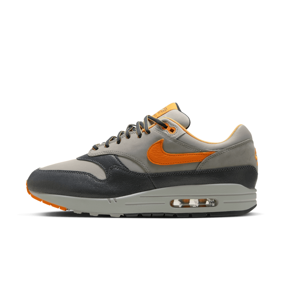 Nike Air Max 1 HUF Brilliant Orange sneaker featuring a mix of grey, black, and bright orange accents with a visible air cushion sole, designed for exclusive sneaker enthusiasts in Europe. The real deal.