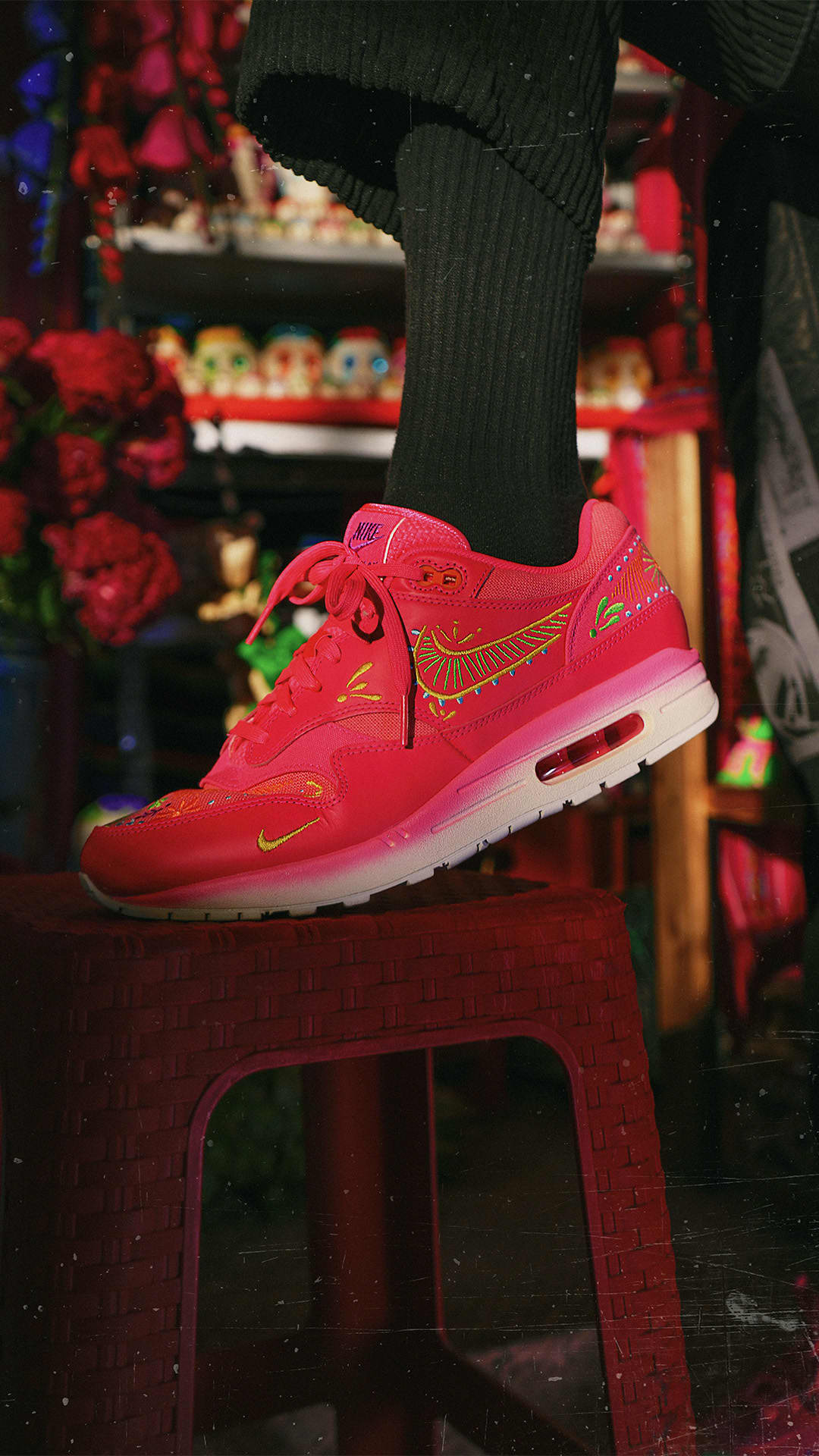 Nike Air Max 1 Dia De Los Muertos sneaker in vibrant red with bright yellow and green accents, styled for an exclusive sneaker collection across Europe. The real deal.