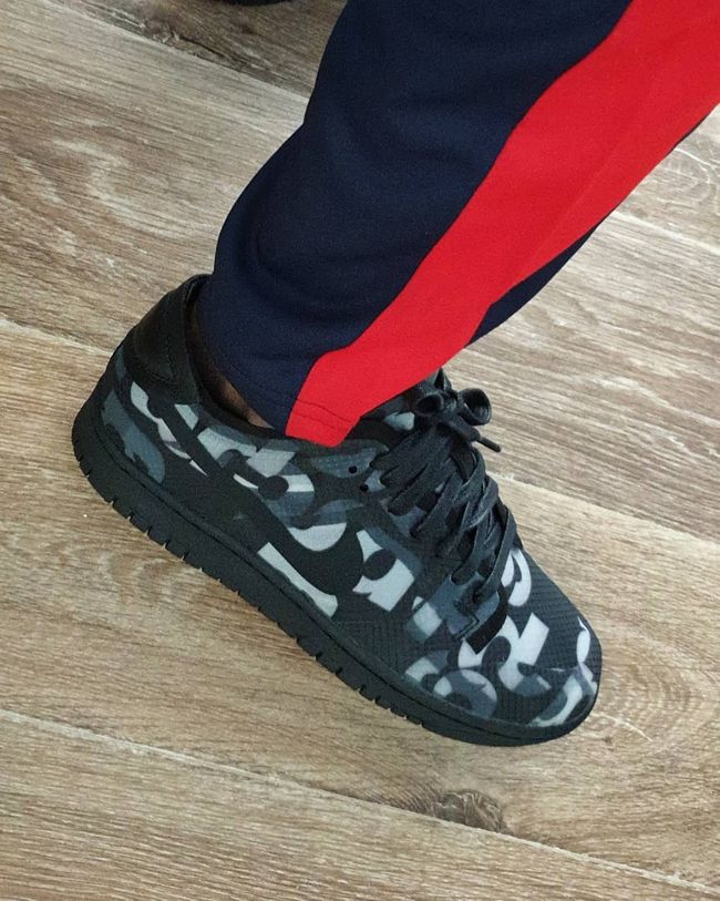 Nike Dunk Low Comme des Garçons Print sneaker in black with bold white abstract patterns, worn with navy and red pants, showcasing exclusive European sneaker style. The real deal.
