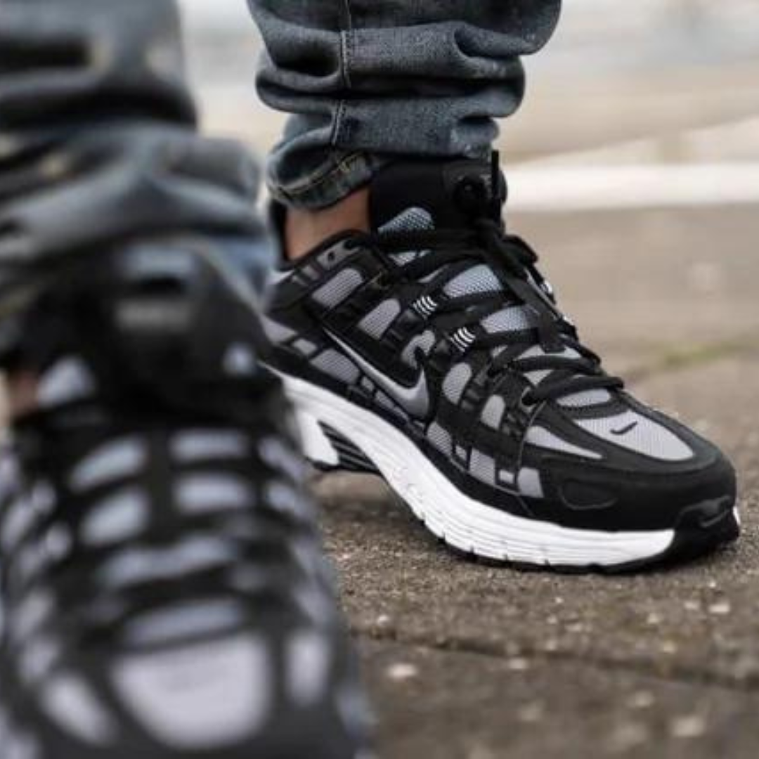 Close-up view of a person wearing Nike P-6000 Black Cool Grey sneakers on a street, showcasing the exclusive sneaker design and stylish contrast of black and cool grey tones.