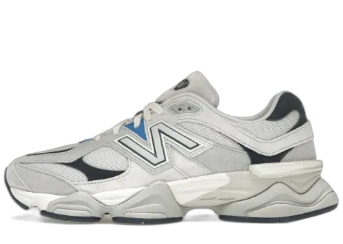 New Balance 9060 Grey Blue, zijaanzicht met witte en grijze kleurvlakken, zwarte accenten en blauwe N-logo, chunky zool