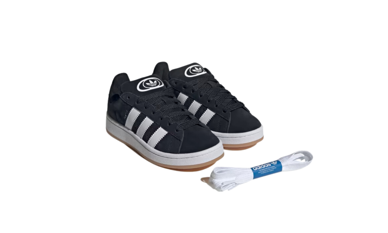 Pair of Adidas Campus 00s GS Core Black Kids sneakers in black with white stripes and gum sole, alongside an extra set of white shoelaces, the real deal exclusive in Europe.