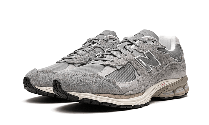 Pair of New Balance 2002R Protection Pack Grey sneakers featuring layered grey suede and mesh upper with white cushioned sole, designed for comfort and style—the real deal in exclusive European trainers.