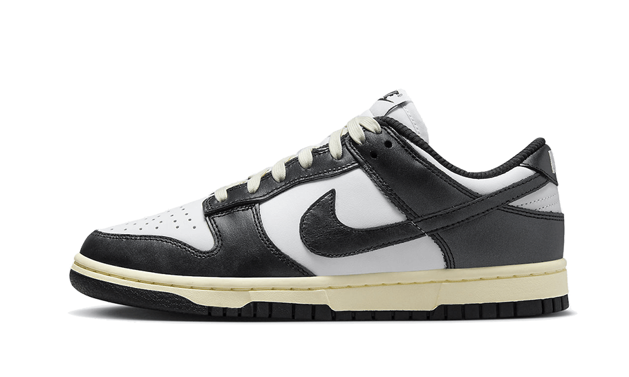 Side view of a Nike Dunk Low Vintage Panda sneaker in black and white with cream-colored midsole, showcasing its classic low-top design and exclusive European sneaker style.