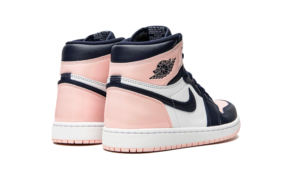 Pair of Nike Air Jordan 1 High OG Atmosphere sneakers in white, soft pink, and navy, shown from the back and side with detailed leather panels. The real deal.