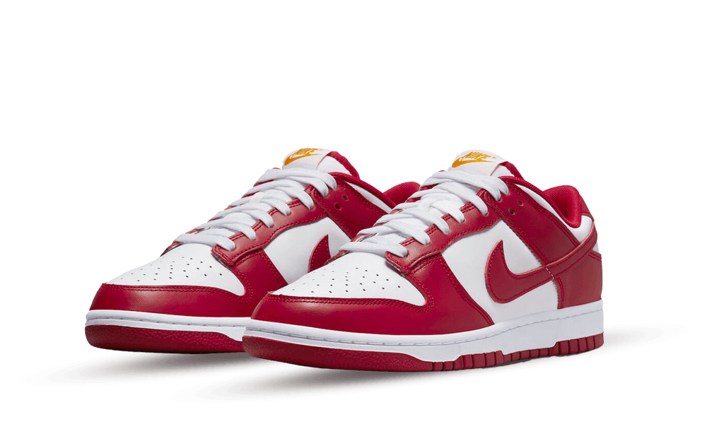 Pair of Nike Dunk Low USC sneakers in red and white leather with white laces, showcasing a sporty and classic design. The real deal exclusive for Europe.